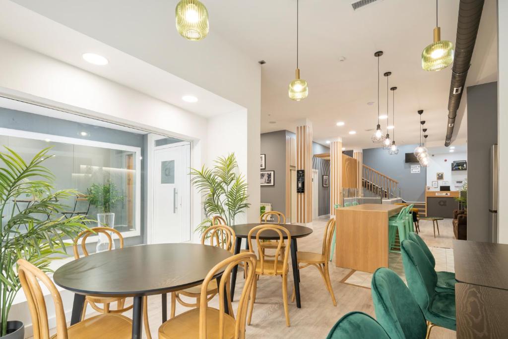 Un comedor con mesas y sillas y una cocina. en Albergue Alda Pilgrim Ponferrada, en Ponferrada