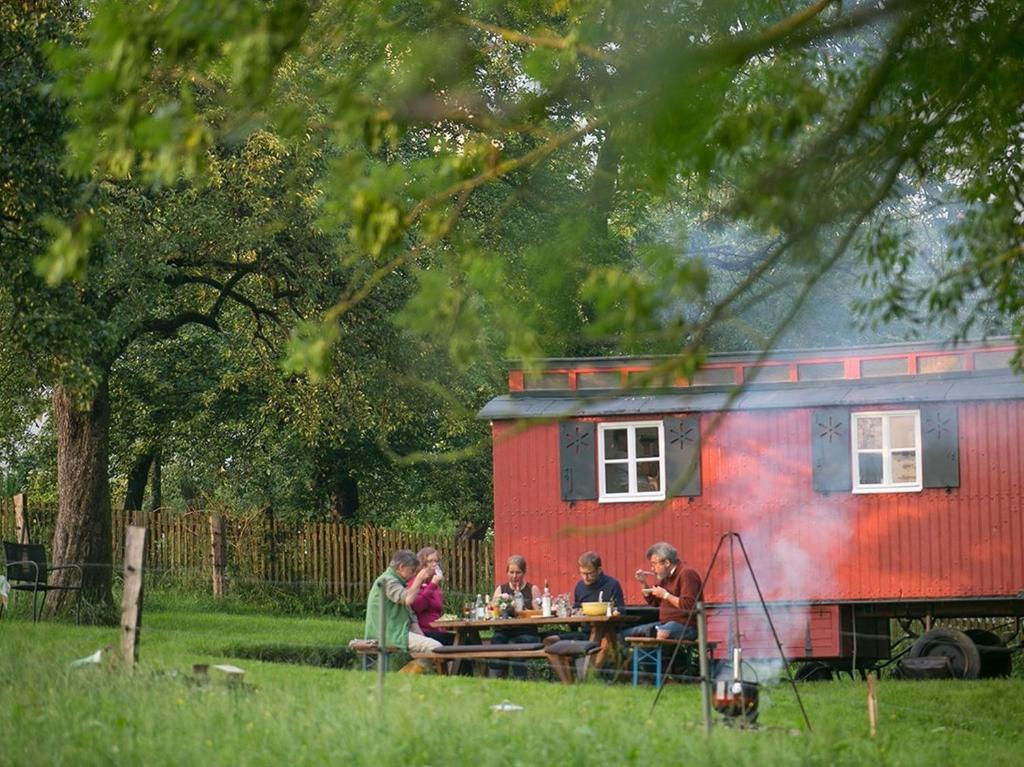 um grupo de pessoas sentadas numa mesa em frente a um trailer em Bauwagen unterm Birnbaum em Lennestadt