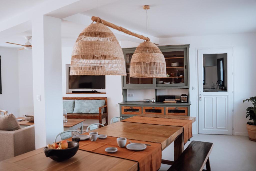 a kitchen with a wooden table and two chandeliers at Biarritz Surf Lodge Chambre d'hôtes in Biarritz