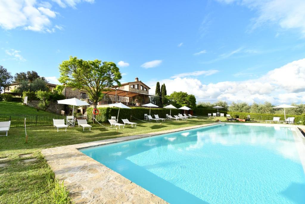 una piscina con sillas y una casa en el fondo en Le Rocche Di Valiano, en Valiano 