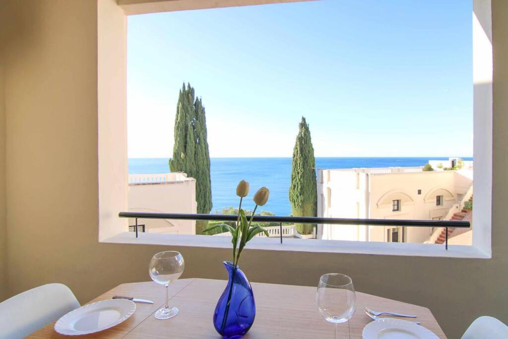 a table with two glasses and a vase with flowers on it at Apartamento con vistas al mar - Anfiteatro 18 in Calpe
