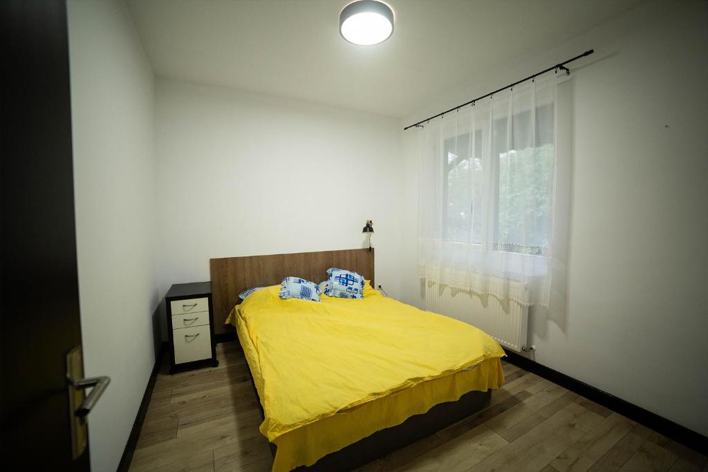 ein Schlafzimmer mit einem gelben Bett und einem Fenster in der Unterkunft Doispe Nuci in Bistra Mureşului