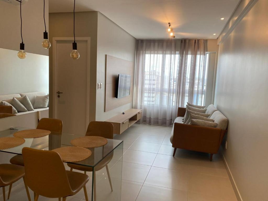 een woonkamer met een tafel, stoelen en een bank bij Edifício Promenade II Apto 1106-Mandi Hospitalidade in Maceió