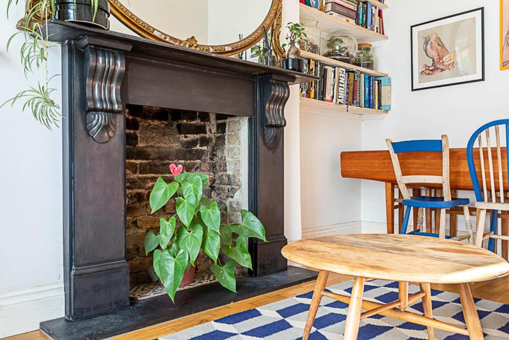 a living room with a fireplace and a table and chairs at Charming Acton Dollhouse in London