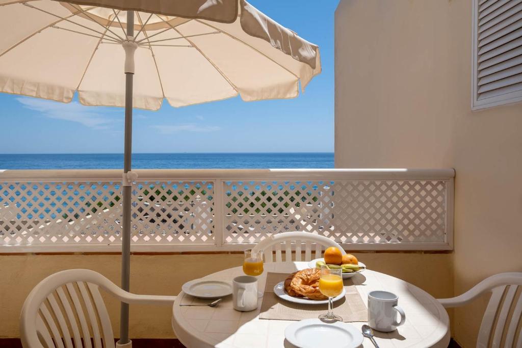stół z talerzem jedzenia i parasolką w obiekcie Pueblo Marina Seaside Apartaments by Alfresco Stays w mieście Mijas Costa
