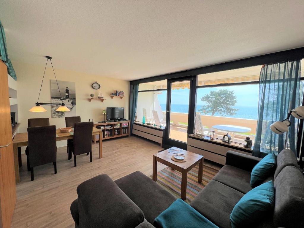 een woonkamer met een bank en een tafel met uitzicht op de oceaan bij Ferienpark Sierksdorf App 61 - Strandlage in Sierksdorf