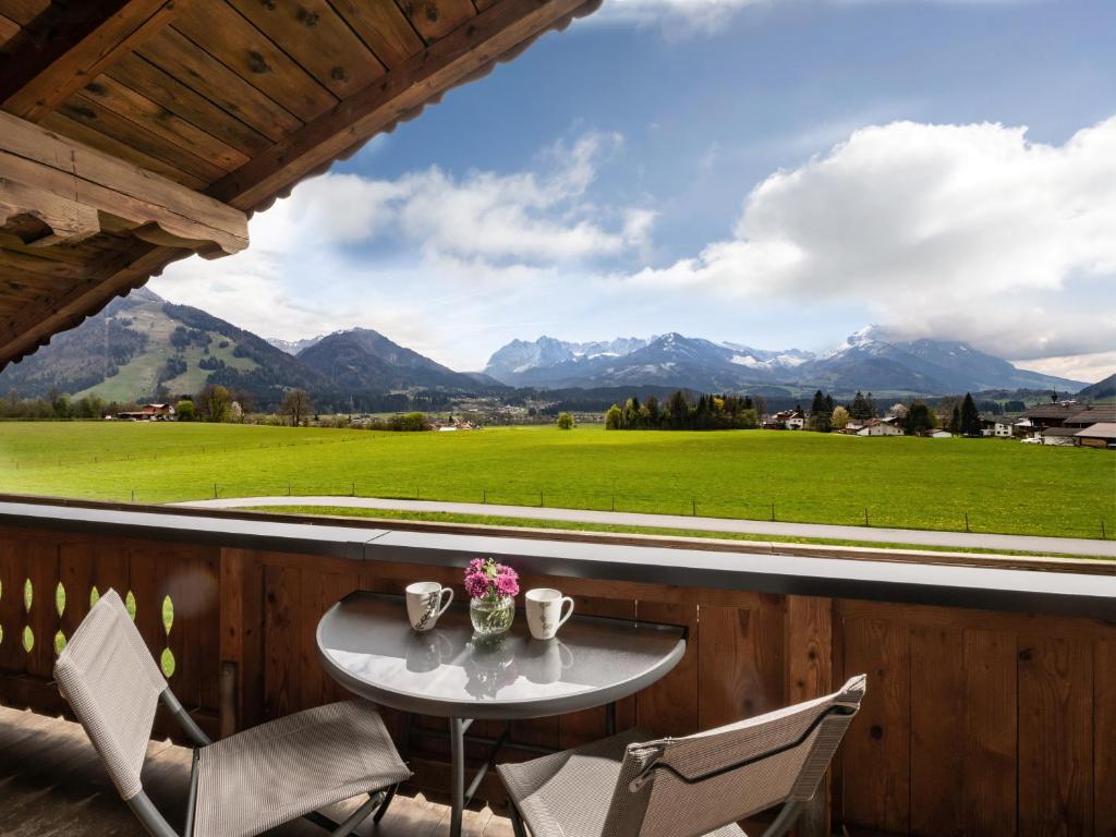 a table and chairs on a balcony with mountains at Ferienwohnung Waldesruh in Kössen