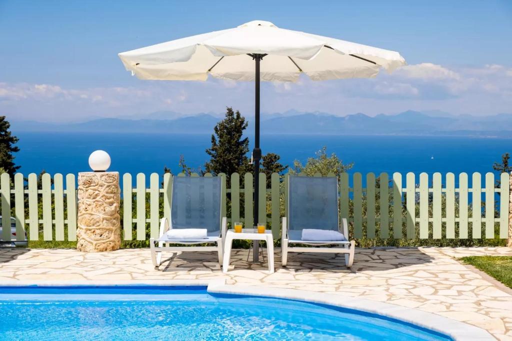 - deux chaises et un parasol à côté de la piscine dans l'établissement Gkountis Apartments, à Tsoukaladhes