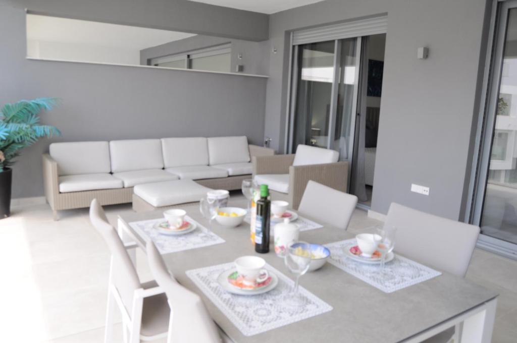 een woonkamer met een tafel en stoelen en een bank bij Apartamento Vanian Gardens Estepona in Estepona