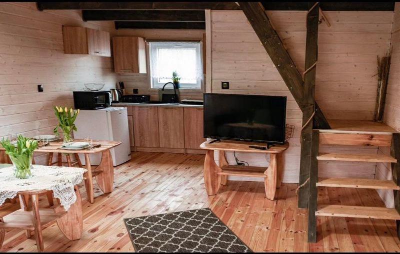 ein Wohnzimmer mit einem TV und einer Küche in der Unterkunft Domki u Tutki in Szklarska Poręba