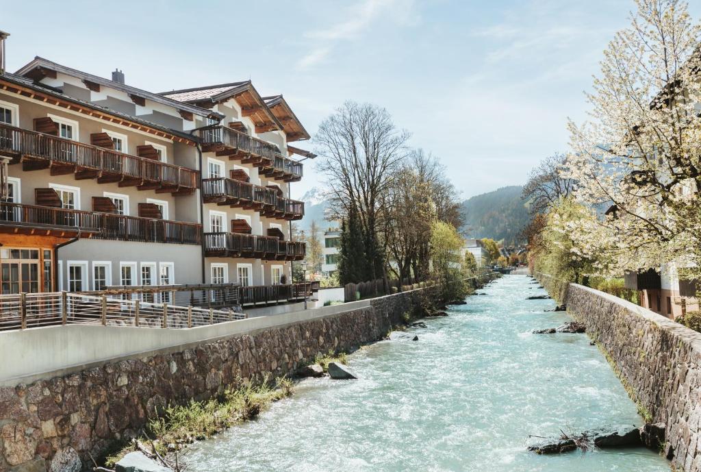 a river in front of buildings next to a river at HENRI Country House Kitzbühel in Kitzbühel