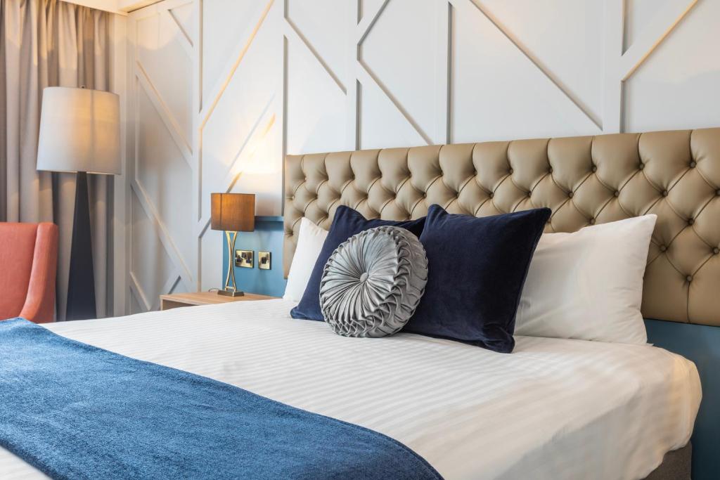 um quarto com uma cama grande e almofadas azuis e brancas em The Queen at Chester Hotel, BW Premier Collection em Chester