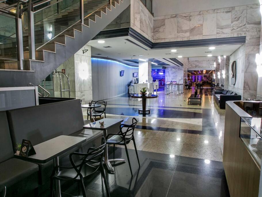a lobby with tables and chairs and a staircase at Flat Mercure 1km do Planalto Central h07 in Brasilia
