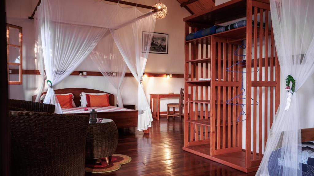 een kamer met een bed en een slaapkamer met gordijnen bij Hotel Ambalakely in Ambalakely