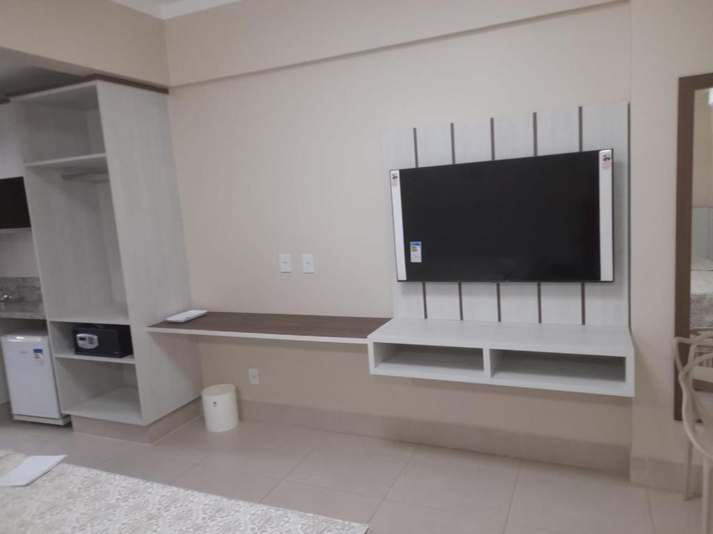 a living room with a flat screen tv on a wall at SPAZZIO DiROMA HOTEL COM ACESSO AO ACQUA PARK in Caldas Novas