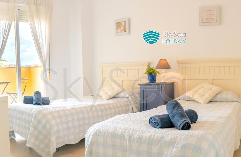two beds in a bedroom with blue pillows on them at Sky Sea Holidays MIJAS COSTA in La Cala de Mijas