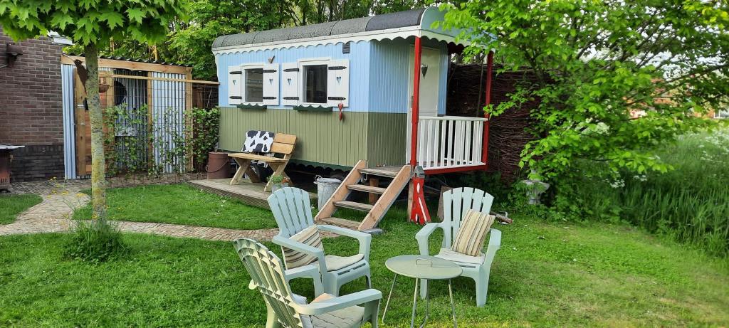 a group of chairs and a tiny house in a yard at Pipowagen 