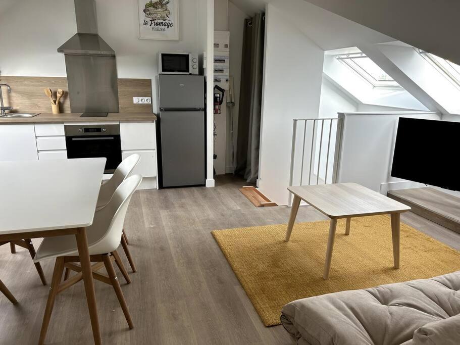 a living room with a table and a kitchen at Charmant appartement chez Pat in Caen