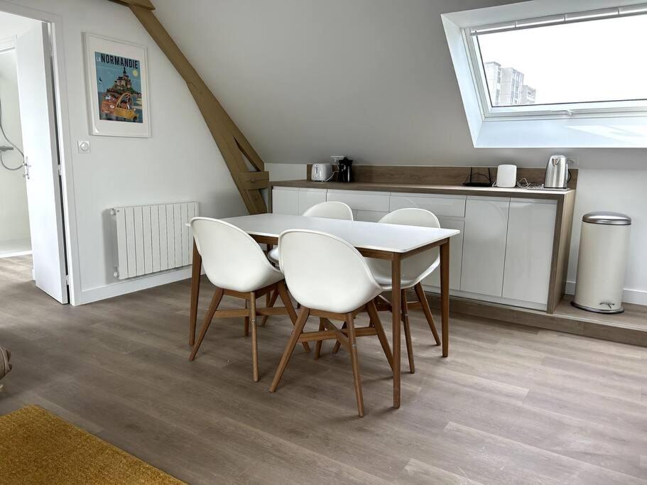 a dining room with a table and white chairs at Charmant appartement chez Pat in Caen