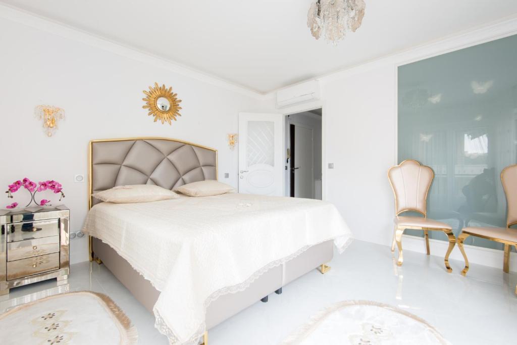 a white bedroom with a bed and a chair at La Perle Bleue - Central - Vue Mer - Wifi in Roquebrune-Cap-Martin