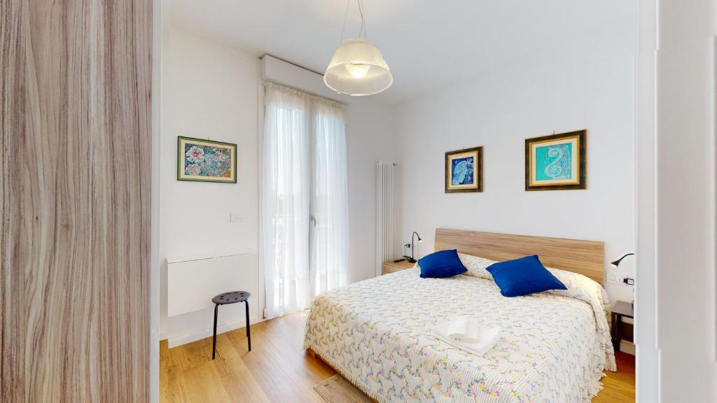a white bedroom with a bed with blue pillows at Avantgard Rooms S. Orsola in Bologna