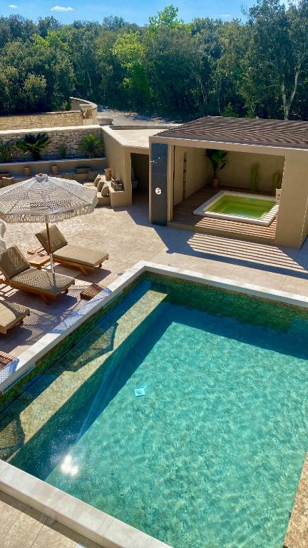 une piscine avec des chaises et une maison dans l'établissement La Maison d'Ambrine - La Villa Ibiza, à Chamaret