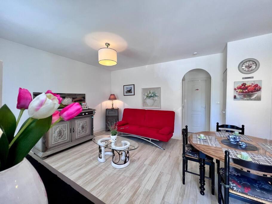 - un salon avec un canapé rouge et une table dans l'établissement Maison des Papillons - Jolie Maison - Proche Centre Brive, à Brive-la-Gaillarde
