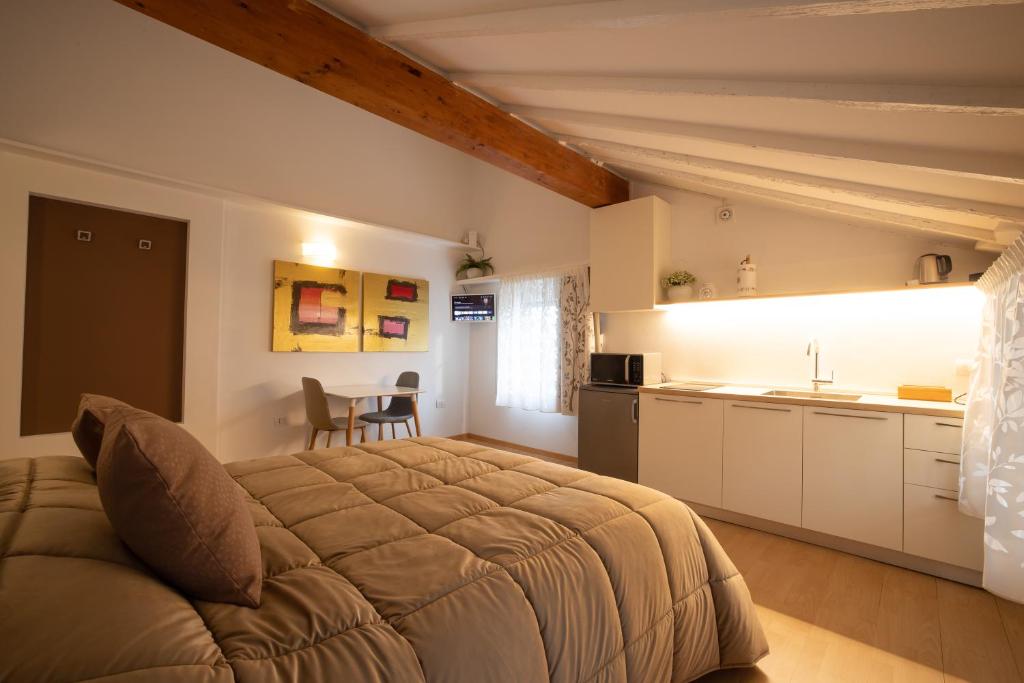 a bedroom with a large bed and a kitchen at Monolocale adiacente al centro con posto auto in Schio
