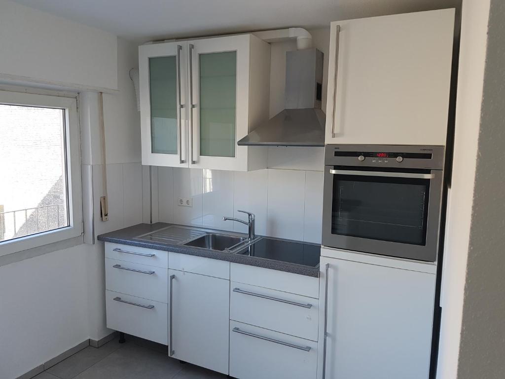 een keuken met witte kasten, een wastafel en een fornuis bij Joanna Apartment- MA City 1 in Mannheim