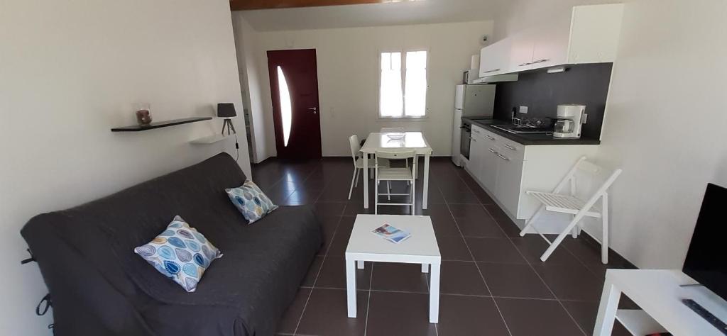 un salon avec un canapé noir et une cuisine dans l'établissement MAISON ROUGE LE PONANT, à Châtelaillon-Plage