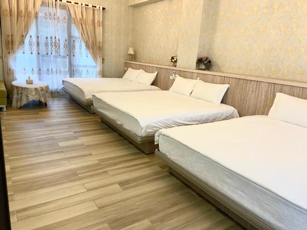 a room with three beds and a table at 花蓮漫漫時光電梯包棟民宿 in Hualien City