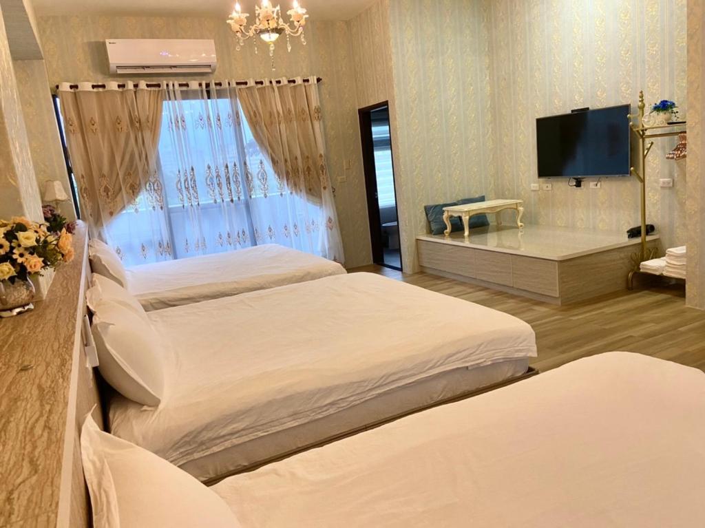 a hotel room with two beds and a flat screen tv at 花蓮漫漫時光電梯包棟民宿 in Hualien City