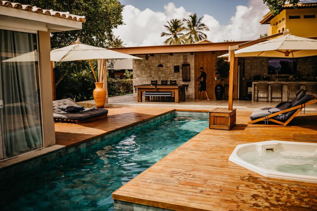 einen Pool mit einer Holzterrasse mit einem Sonnenschirm in der Unterkunft Beach House Sauípe in Costa do Sauipe