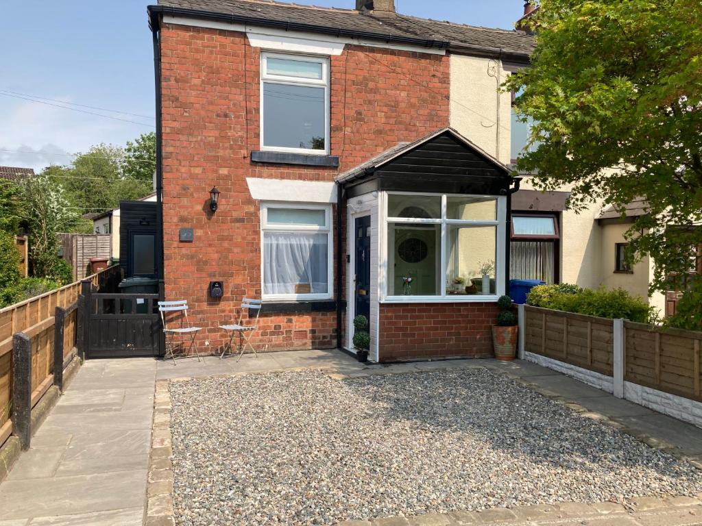 a red brick house with a patio in front of it at Adlington Cottage, Lancashire in Adlington