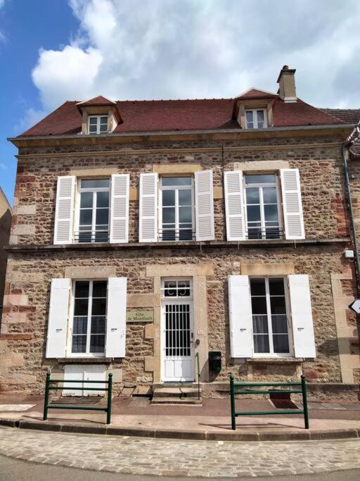 un vecchio edificio in mattoni con due panchine di fronte di Gîte de groupe 2 à 12 personnes a Guillon