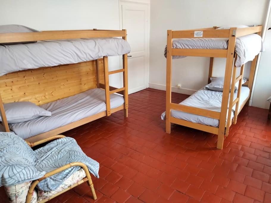 una stanza con due letti a castello e un pavimento in mattoni rossi di Gîte de groupe 2 à 12 personnes a Guillon