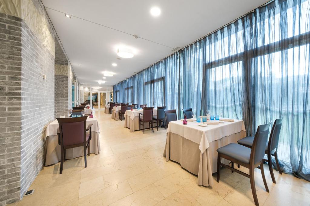a dining room with tables and chairs and windows at Castilla Termal Solares in Solares