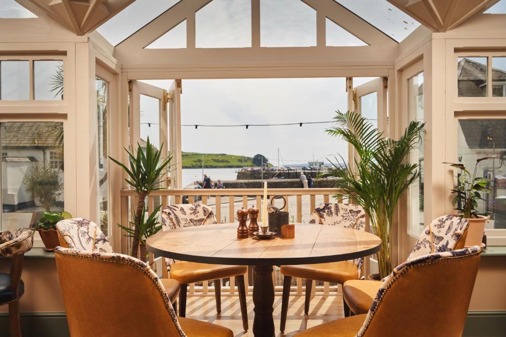 a screened in porch with a table and chairs at The Rising Sun in Saint Mawes