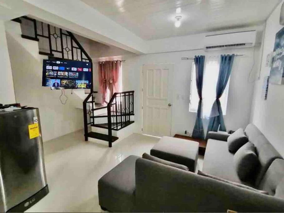 a living room with a couch and a television at Full Aircon Camella House w/ wifi Netflix hotwater in Butuan