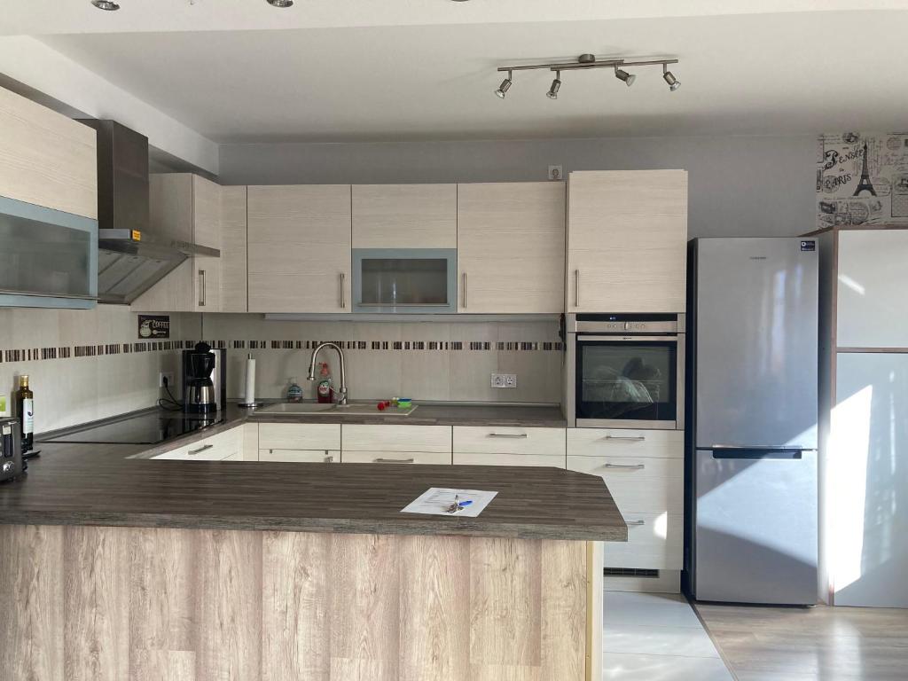 a kitchen with white cabinets and a stainless steel refrigerator at Große Wohnküche, Terrasse, Schlafzimmer am Steinhuder Meer, WLAN, Parkplatz, Fußbodenheizung, 70qm in Wunstorf