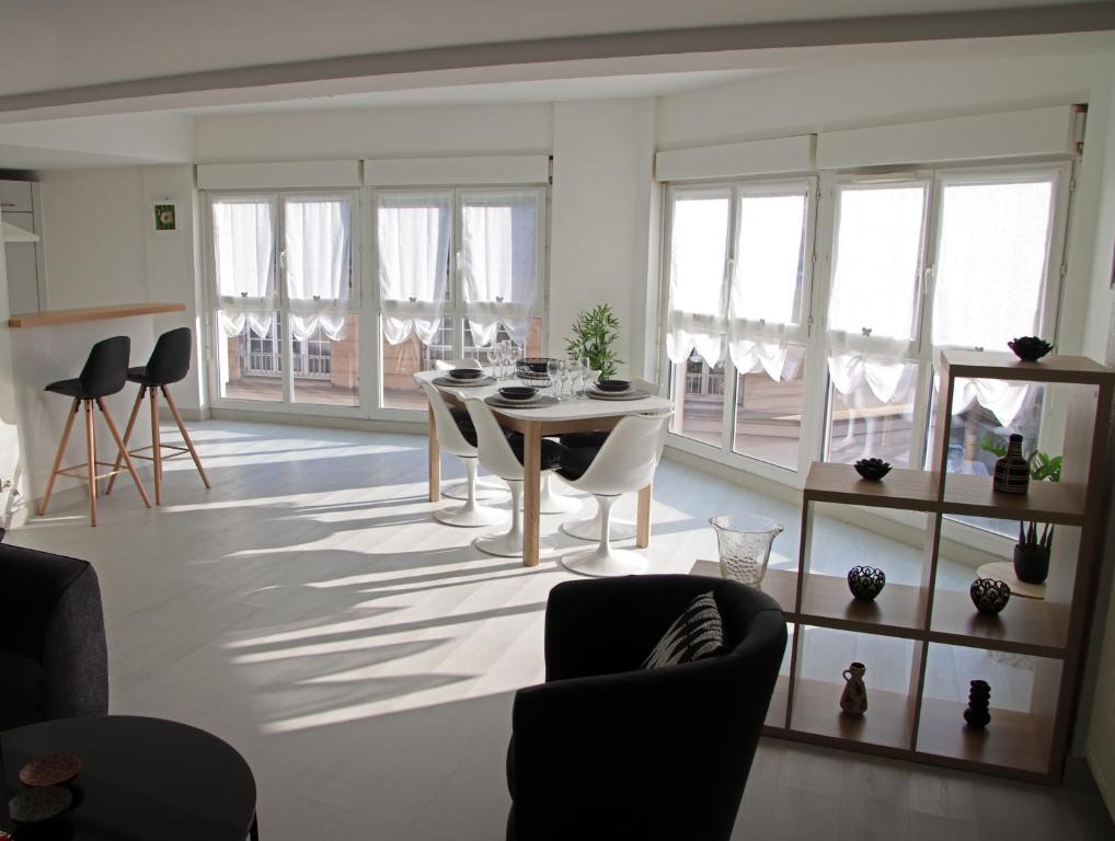 een woonkamer met een tafel, stoelen en ramen bij GINA Epernay Hyper-Centre 2-4 P in Épernay