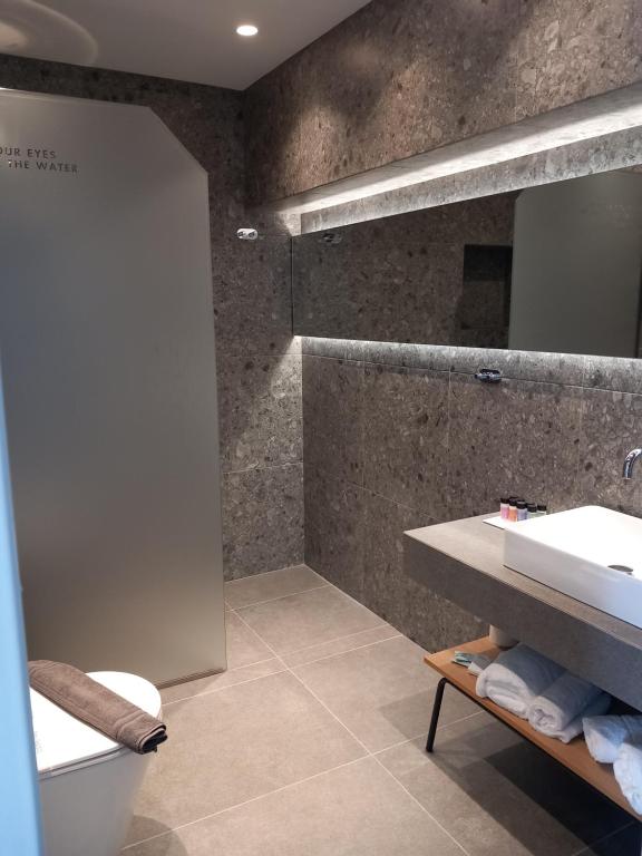 a bathroom with a sink and a toilet and a mirror at Bianco Hotel in Lakkíon