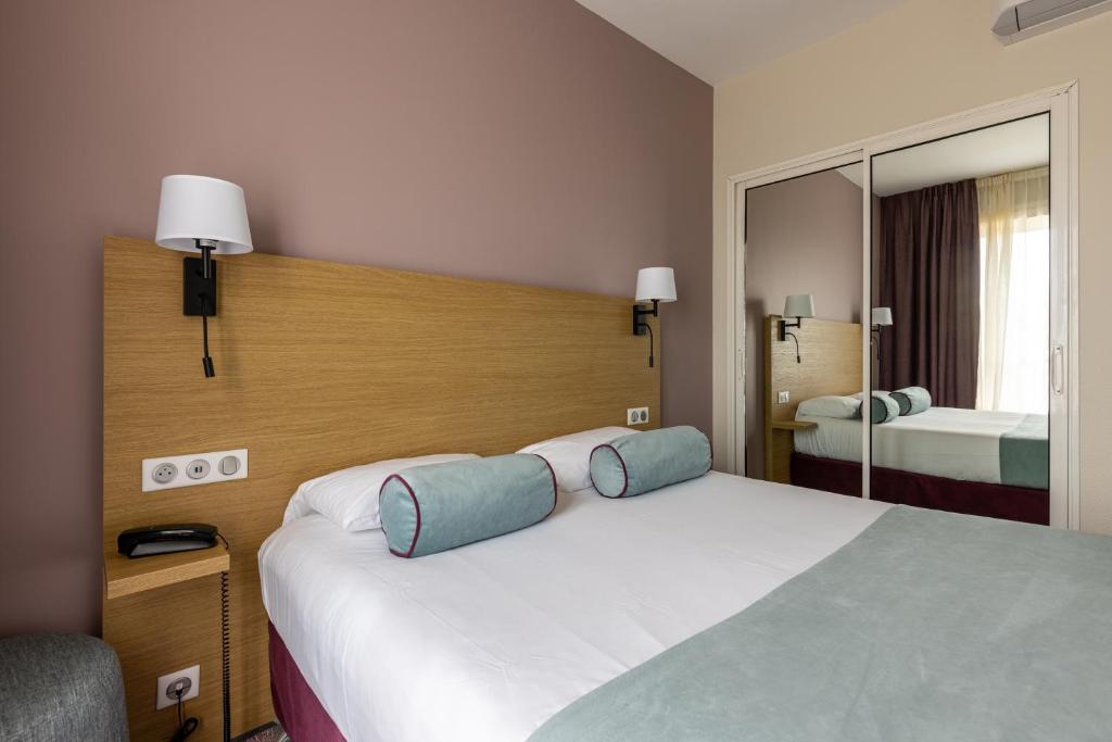 a hotel room with a large bed and a mirror at Brit Hotel Europ Bergerac in Bergerac
