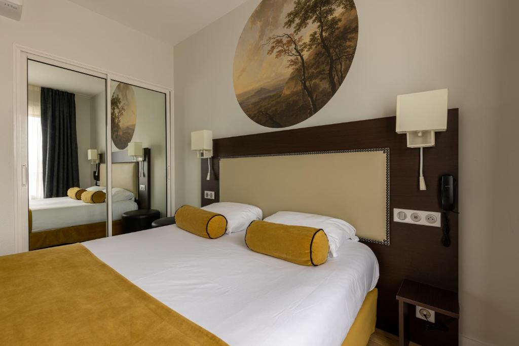 a bedroom with a large white bed with yellow pillows at Brit Hotel Europ Bergerac in Bergerac