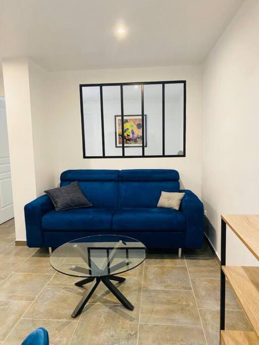 - un canapé bleu dans le salon avec une table en verre dans l'établissement Toulouse centre 4 couchages, à Toulouse