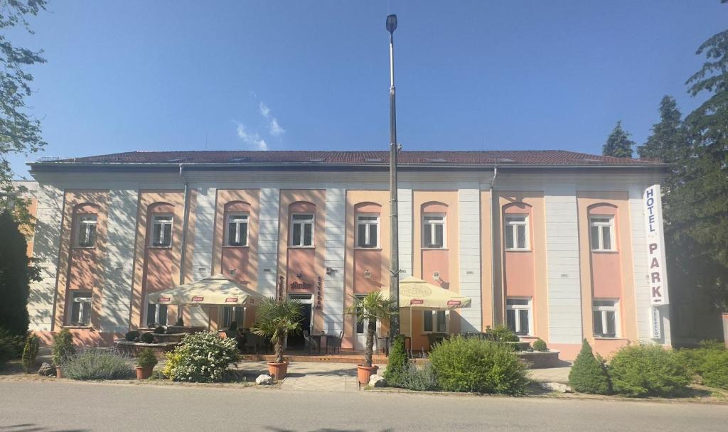 um grande edifício com uma bandeira em frente em Park Hotel em Nagyatád