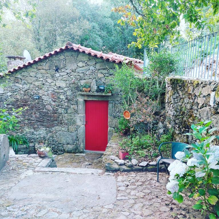 a small stone building with a red door at Moinho do Formigal in Valença