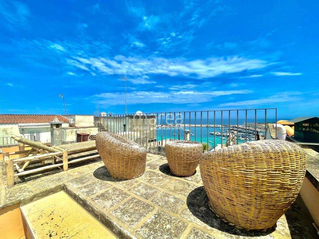 un gruppo di sedie in vimini seduti sopra un balcone di La Torretta - Marea Collection a Otranto