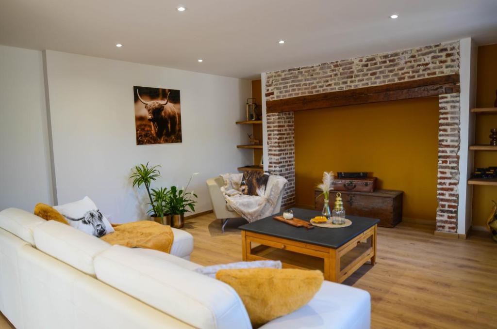 - un salon avec un canapé blanc et une cheminée en briques dans l'établissement Le Quai Huppé, voie 3, à Noyelles-sur-Mer