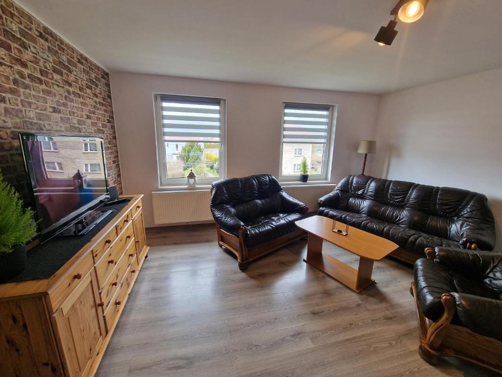 een woonkamer met lederen meubels en een flatscreen-tv bij Przestronny apartament +siłownia in Bytom